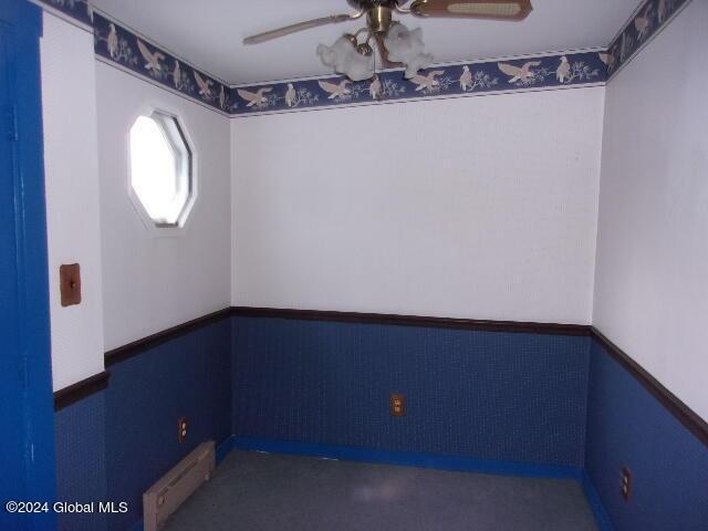 2119 Broadway, Schenectady, NY 12306 - empty room with a wainscoted wall, baseboard heating, and a ceiling fan