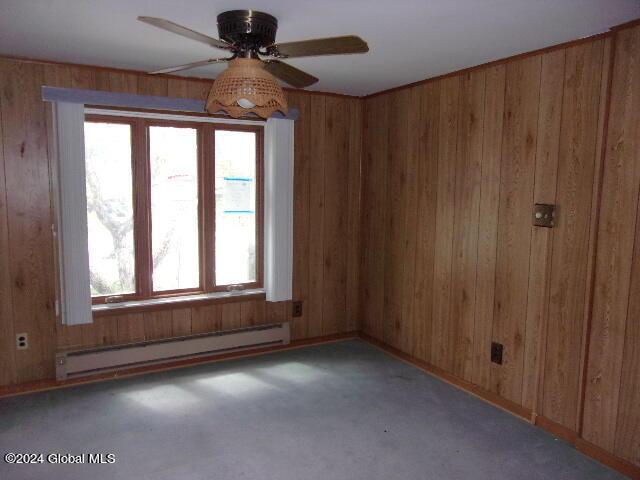 2119 Broadway, Schenectady, NY 12306 - empty room featuring carpet floors, a baseboard radiator, wood walls, and ceiling fan