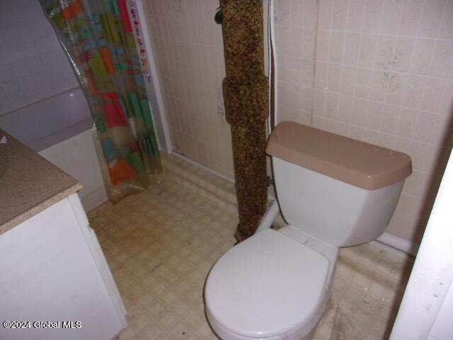 2119 Broadway, Schenectady, NY 12306 - bathroom featuring tile walls, toilet, tile patterned floors, and curtained shower