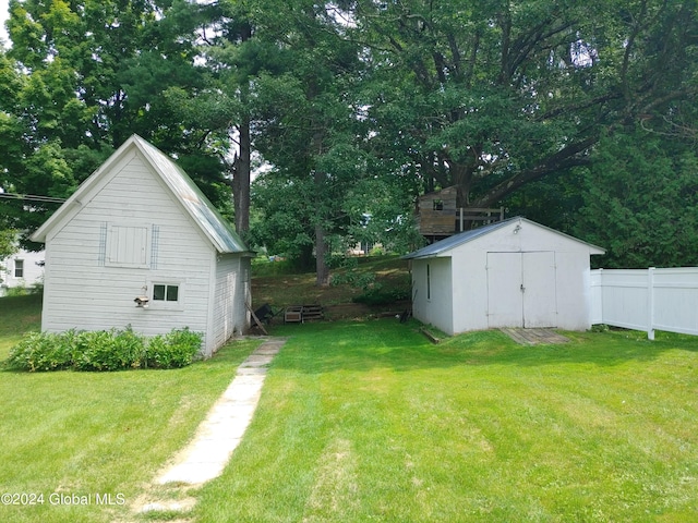 view of yard featuring fence, a storage unit, and an outdoor structure