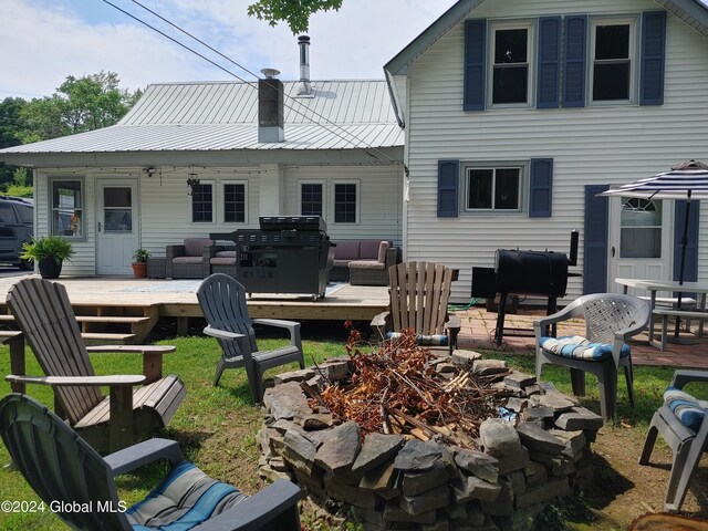 rear view of property with an outdoor living space with a fire pit and a deck