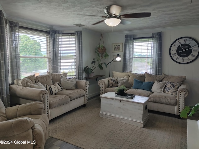 living area with a textured ceiling, visible vents, ornamental molding, and a ceiling fan