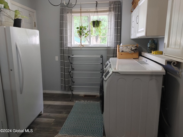 clothes washing area with washer and clothes dryer, cabinet space, dark wood-type flooring, and baseboards