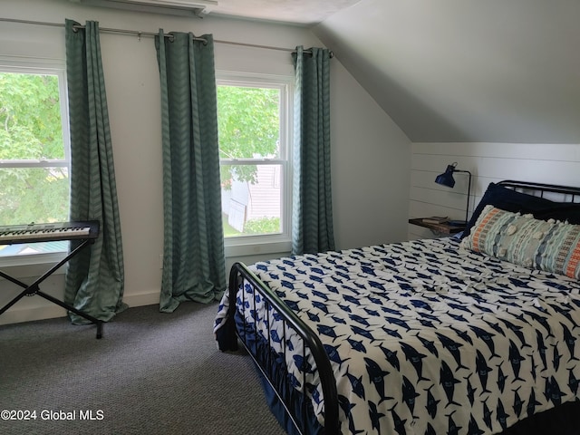 bedroom with multiple windows, lofted ceiling, wooden walls, and carpet floors