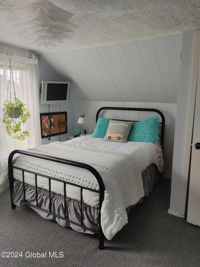 carpeted bedroom with vaulted ceiling and a textured ceiling