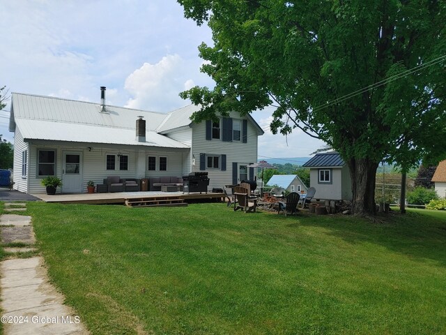 rear view of house featuring a wooden deck and a lawn