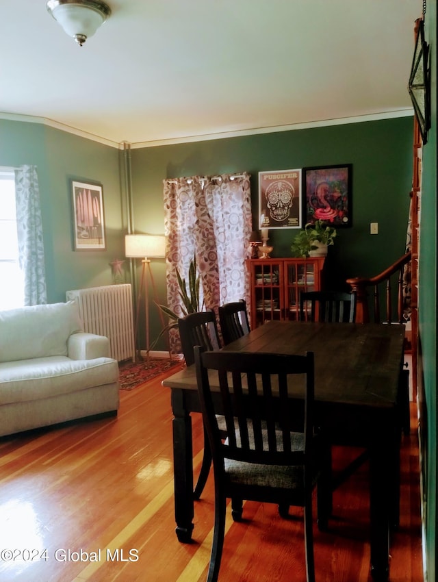 dining area with radiator, wood finished floors, and ornamental molding