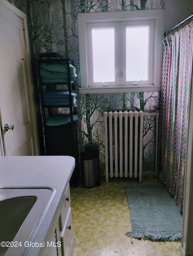 interior space with wallpapered walls, radiator heating unit, and a sink