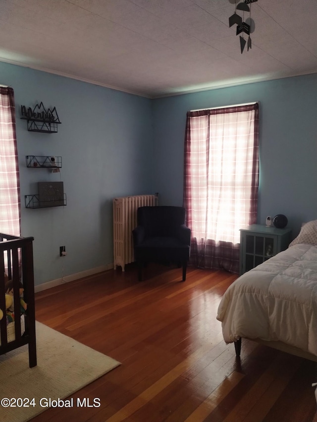 bedroom featuring radiator, baseboards, and wood finished floors