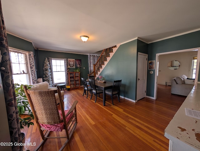 dining room with stairway, ornamental molding, a healthy amount of sunlight, and hardwood / wood-style floors