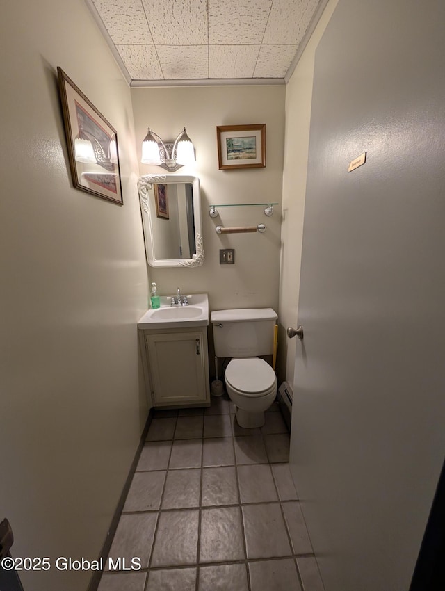 bathroom with toilet, tile patterned flooring, a baseboard radiator, a paneled ceiling, and vanity