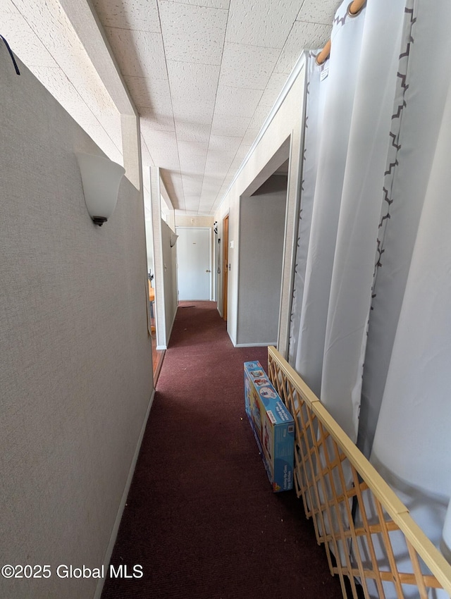 corridor with rail lighting, baseboards, and carpet floors