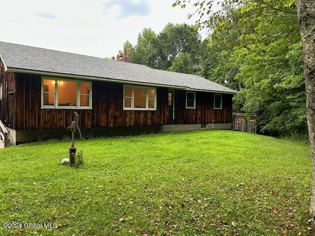 view of front of home with a shingled roof and a front lawn