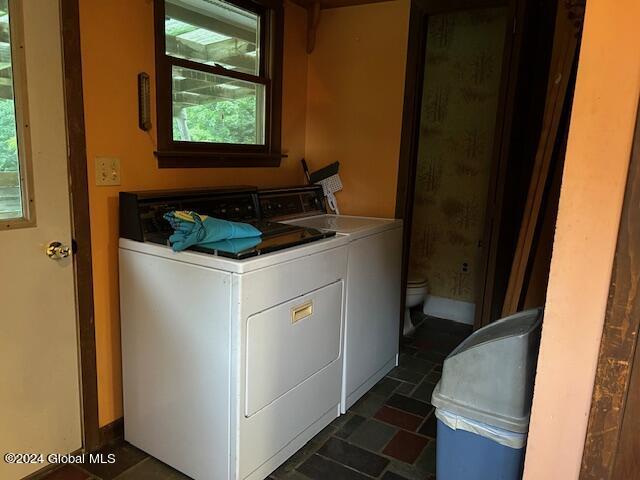 clothes washing area with stone finish flooring and independent washer and dryer