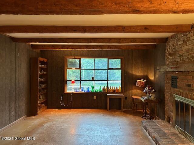 interior space with beamed ceiling, a fireplace, and wooden walls