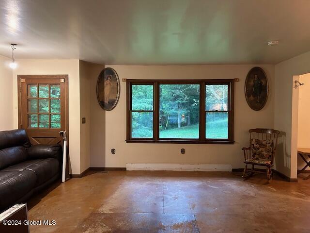 living area with a healthy amount of sunlight, concrete floors, and baseboards