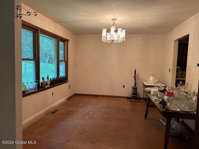 unfurnished dining area featuring baseboards, concrete floors, visible vents, and a notable chandelier