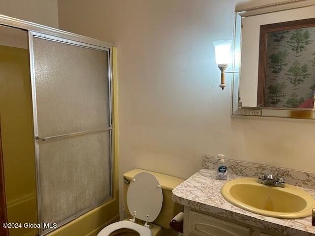 bathroom with toilet, bath / shower combo with glass door, and vanity