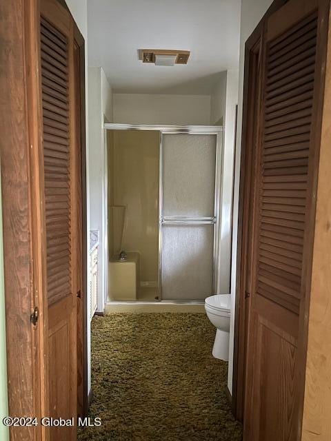 bathroom with toilet, a stall shower, visible vents, and a closet