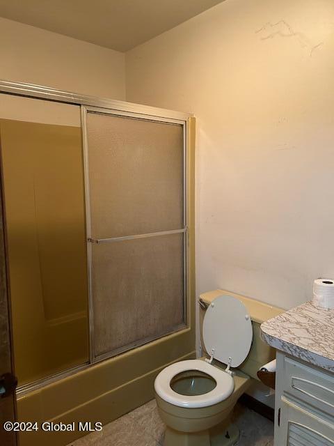 bathroom with toilet, combined bath / shower with glass door, and vanity