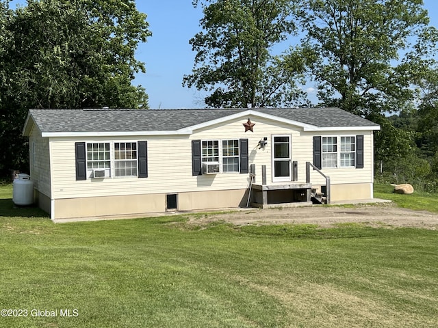 manufactured / mobile home featuring driveway, roof with shingles, cooling unit, and a front yard