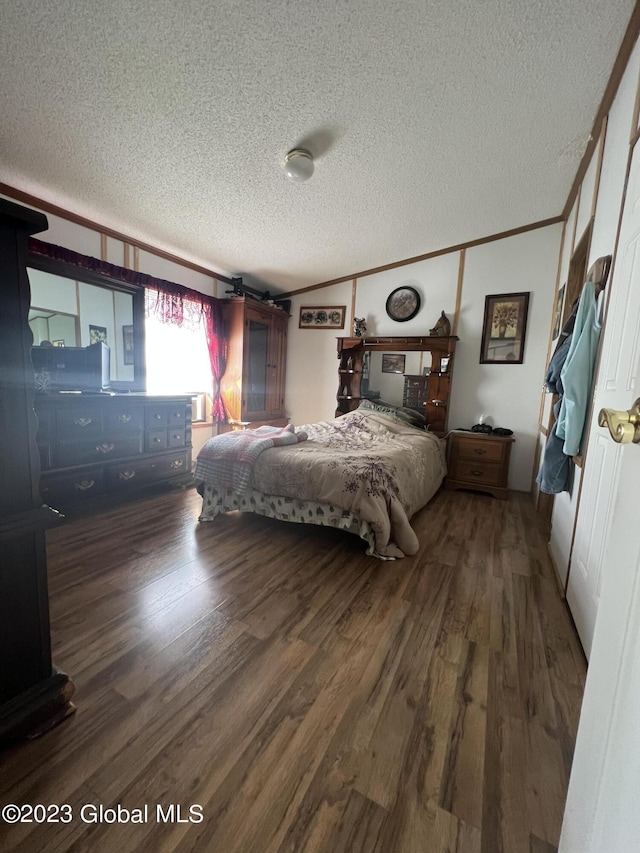 bedroom featuring a textured ceiling, ornamental molding, and wood finished floors