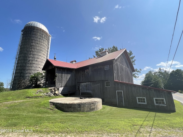 view of property exterior with an outbuilding, a chimney, a lawn, metal roof, and a barn