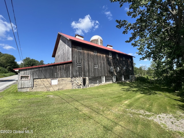 view of side of property featuring a barn, a chimney, an outdoor structure, and a yard