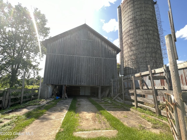 view of home's exterior featuring driveway, fence, an outdoor structure, and an outbuilding