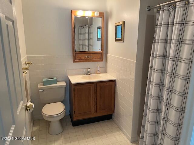 bathroom with tile walls, vanity, curtained shower, and toilet