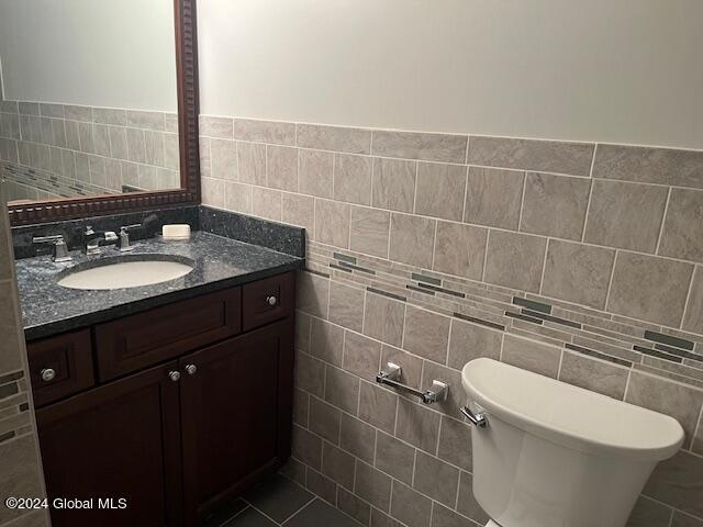 bathroom with tile patterned flooring, vanity, tile walls, and toilet