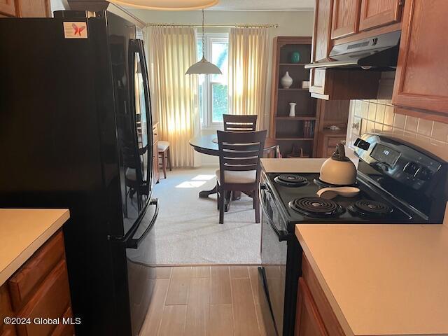 kitchen featuring backsplash, decorative light fixtures, black appliances, and light hardwood / wood-style floors