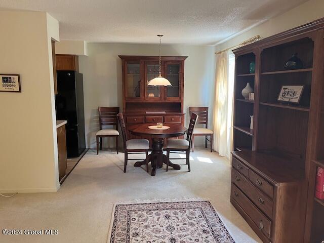 dining space featuring light carpet and a textured ceiling