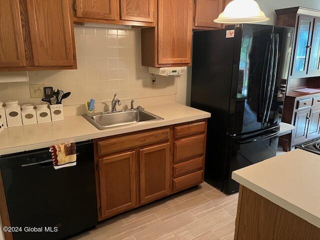 kitchen featuring sink, pendant lighting, decorative backsplash, and black appliances