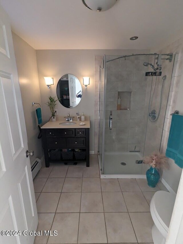 bathroom with vanity, tile patterned floors, a shower with shower door, toilet, and baseboard heating