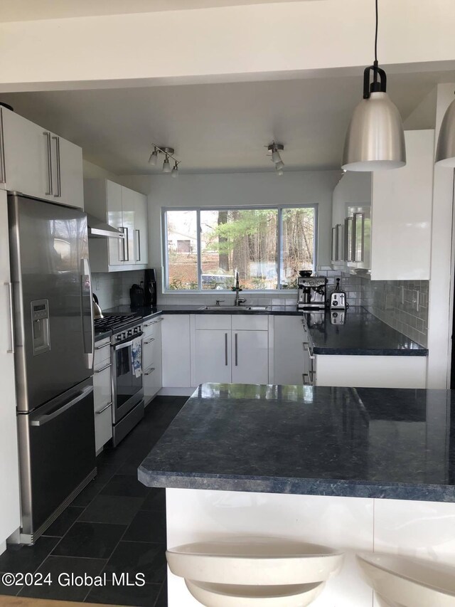 kitchen featuring dark tile patterned floors, white cabinets, appliances with stainless steel finishes, decorative backsplash, and sink