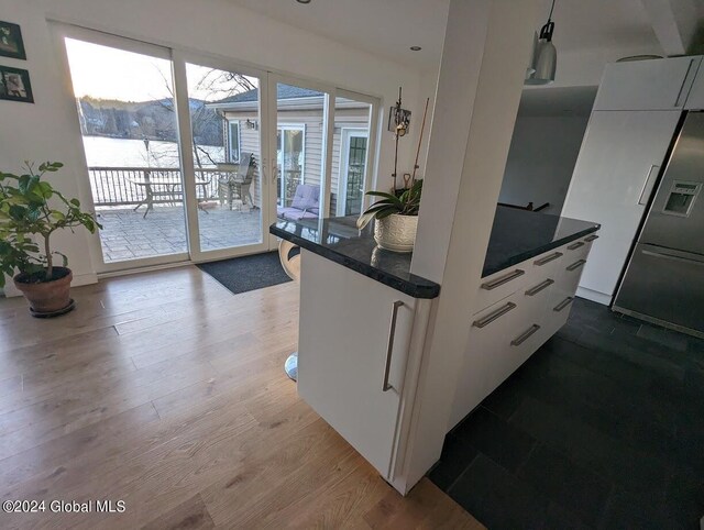 kitchen featuring dark stone countertops, hardwood / wood-style flooring, and white cabinets