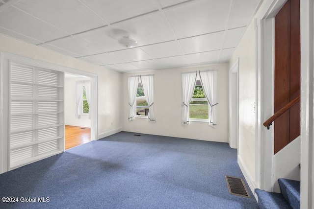 unfurnished room with carpet and a drop ceiling