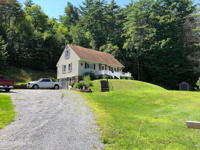 view of front facade featuring covered porch, a storage unit, and a front lawn