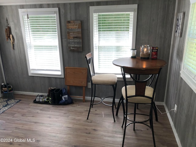 dining space with hardwood / wood-style flooring, wooden walls, and plenty of natural light