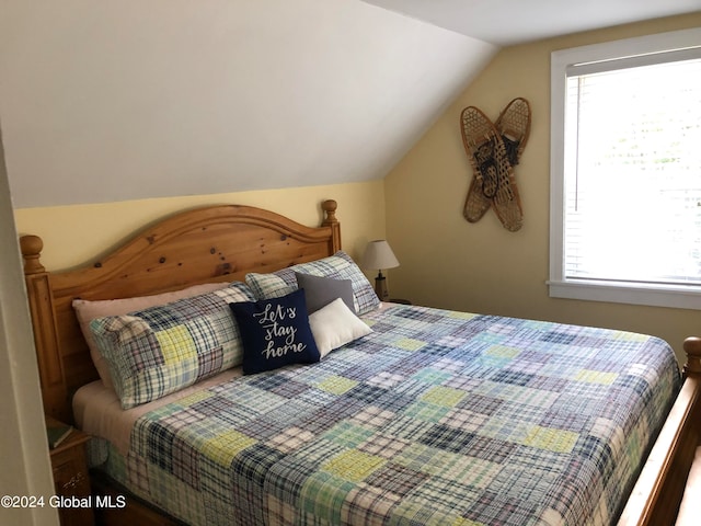 bedroom with lofted ceiling and multiple windows