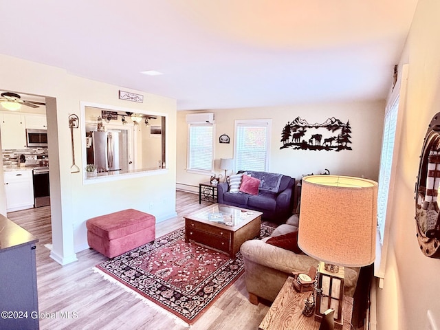 living room featuring light hardwood / wood-style floors, a baseboard radiator, a wall mounted air conditioner, and ceiling fan