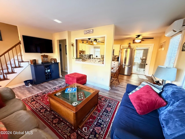 living room featuring a wall mounted air conditioner, hardwood / wood-style flooring, and ceiling fan