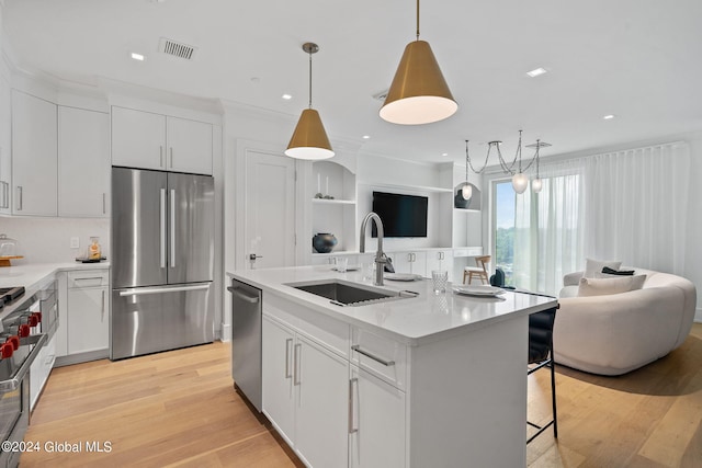 kitchen featuring open floor plan, light wood-type flooring, light countertops, stainless steel appliances, and a sink