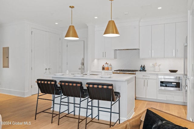 kitchen featuring a sink, white cabinetry, a breakfast bar area, light wood finished floors, and light countertops