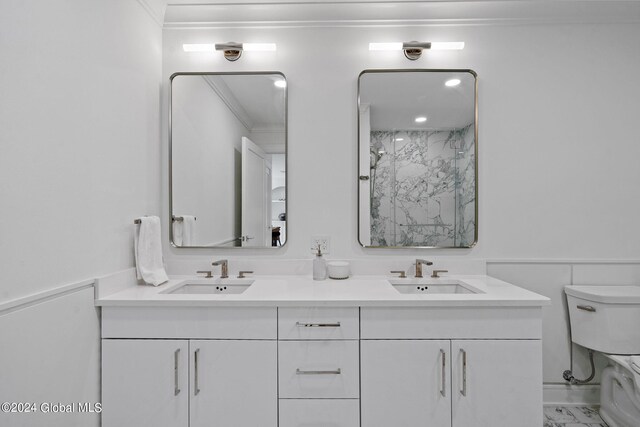 bathroom featuring a sink, toilet, double vanity, and crown molding