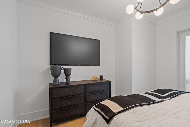 bedroom featuring baseboards, a notable chandelier, ornamental molding, and light wood finished floors