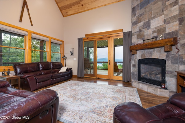 living room featuring high vaulted ceiling, a stone fireplace, and hardwood / wood-style floors