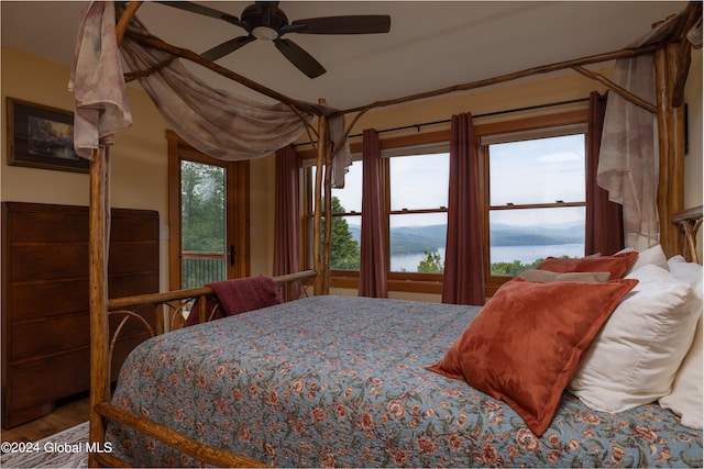 bedroom with access to exterior, a water view, and ceiling fan