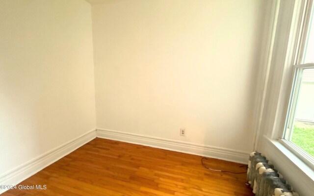 empty room with hardwood / wood-style flooring and radiator